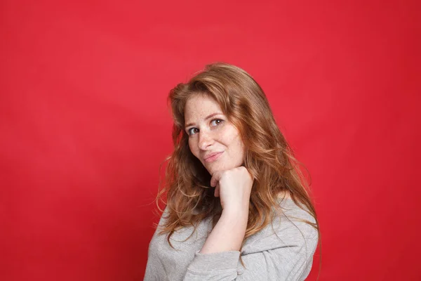 幸せなブルネット女性でグレーセーター立って横に赤の背景 — ストック写真