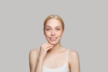 Gri arka planda, gülümseyen muhteşem bir kadın. Güzellik, kozmetik, cilt bakımı, cazibe.