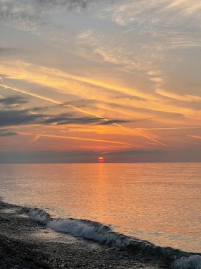 Parlak günbatımı arka planı. Güneş, gökyüzü, bulutlar ve denizle birlikte doğa bileşimi