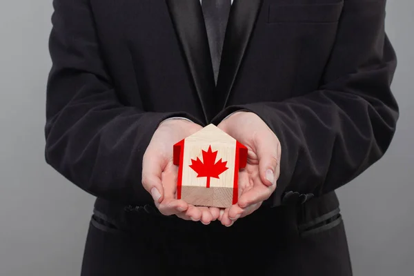 持有悬挂加拿大国旗的木制房屋的加拿大人金融 贷款和信贷概念 — 图库照片