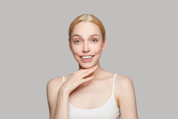 顎に触れる美しい女性の肖像画と灰色の背景に孤立笑顔 化粧品 スキンケア — ストック写真