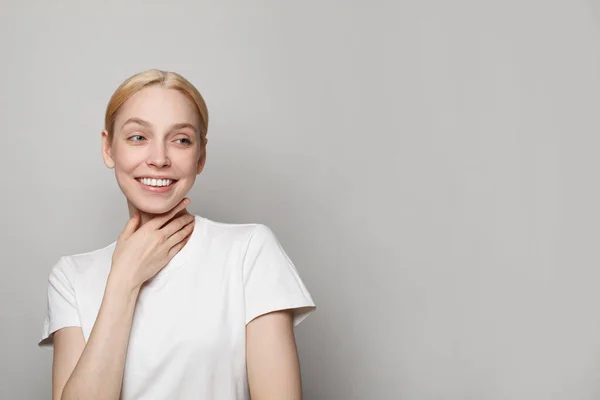 Stock image Young blonde woman in white empty t-shirt looking a side at copy space on white studio wall banner background