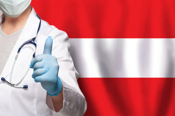 オーストリアの医師の手は オーストリアの背景のフラグに肯定的なジェスチャーを親指アップ表示 — ストック写真