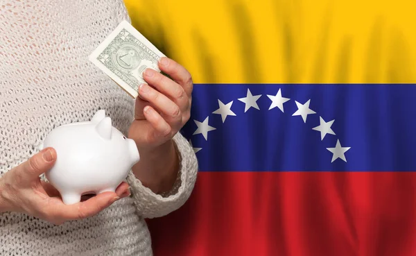 Venezuelan woman with money bank on the background of Venezuela flag. Dotations, pension fund, poverty, wealth, retirement concept