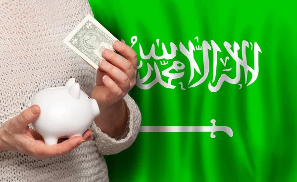 サウジアラビアの国旗を背景にお金の銀行を持つサウジアラビアの女性 年金基金 退職の概念 — ストック写真