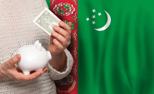 トルクメニスタンの国旗を背景にお金の銀行を持つトルコ人女性 年金基金 退職の概念 — ストック写真