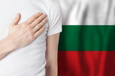Bulgar bayrağının arka planında eli yüreğinde olan Bulgar vatandaşı. Vatanseverlik, ülke, ulusal, gurur konsepti