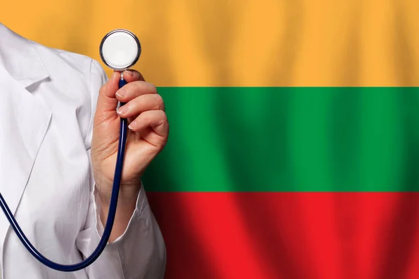 リトアニア医学 診療所 開業医 医療の旗の背景に聴診器を持つリトアニアの医師の手 — ストック写真