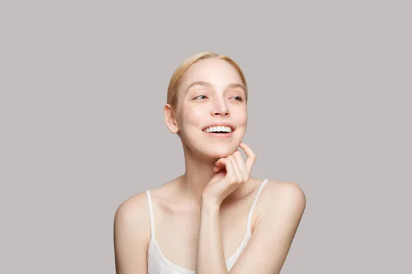 頬に触れる可愛い女性の肖像画と灰色の背景に孤立笑っている 化粧品 スキンケア — ストック写真