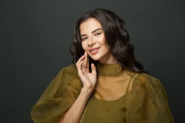 Siyah stüdyo duvarına gülümseyen tatlı bir kadın.