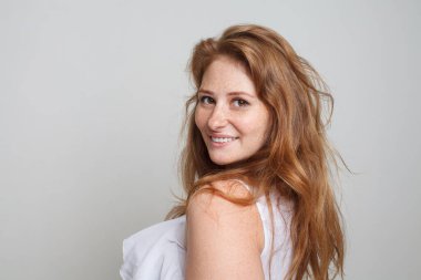 Mutlu model kadın beyaz arka planda kameraya bakıyor.