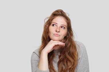 Beyaz arka planda uzun dalgalı saç stili olan düşünceli çekici bir kadın.