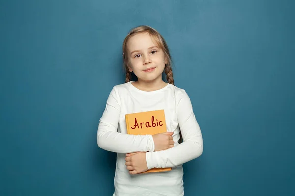 青の黒板の背景にアラビア語の本を持つ子供の学生の女の子 — ストック写真