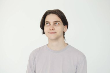 Genç adam beyaz arka planda izole bir şekilde yukarı bakıyor.