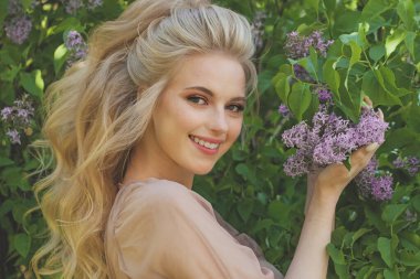 Açık havada sarı dalgalı saçlarıyla mutlu, gülen bir kadın.