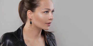 Kulağında siyah taşlı altın küpe Gri pankartta güzel bir model