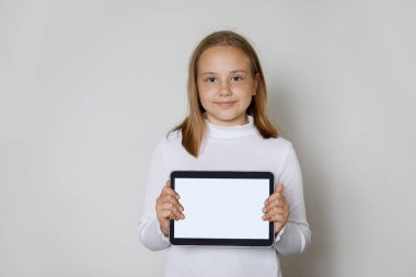 Yeni uygulama veya mobil web sitesi için boş beyaz ekran görüntülü tablet cihazını tutan gülümseyen genç kız çocuğu, Mockup pankartı