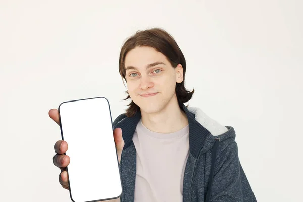 新しいアプリケーションやモバイルウェブサイト モックアップバナーのための空白の画面ディスプレイを持つ大きな空白のスマートフォンで微笑む若者 — ストック写真