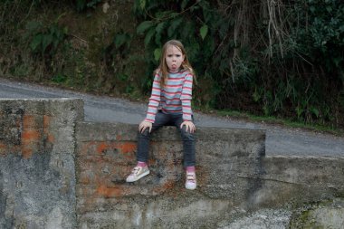 Yaramaz kız dışarıda yüzünü buruşturuyor.