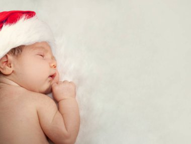 Noel Baba şapkalı yeni doğmuş bebek beyaz arka planda uyuyor.