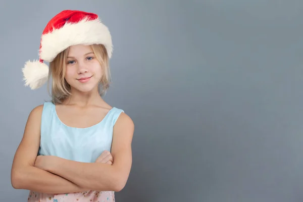 グレーの背景にサンタの帽子のクリスマスの子供の少女 Xmasコンセプト — ストック写真