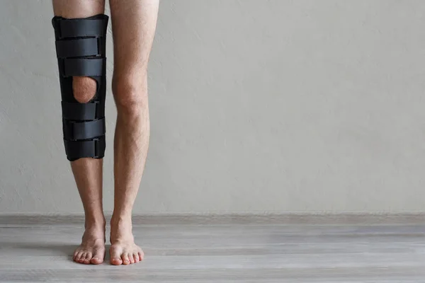 Leg in black knee brace on gray background