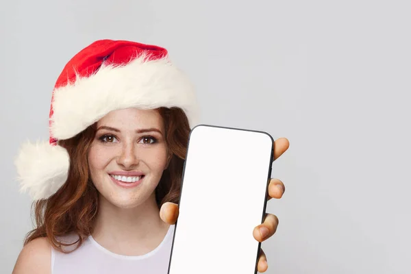 新しいアプリケーションやモバイルウェブサイト モックアップバナーの空白の白い画面ディスプレイでスマートフォンを示すクリスマス女性サンタ — ストック写真
