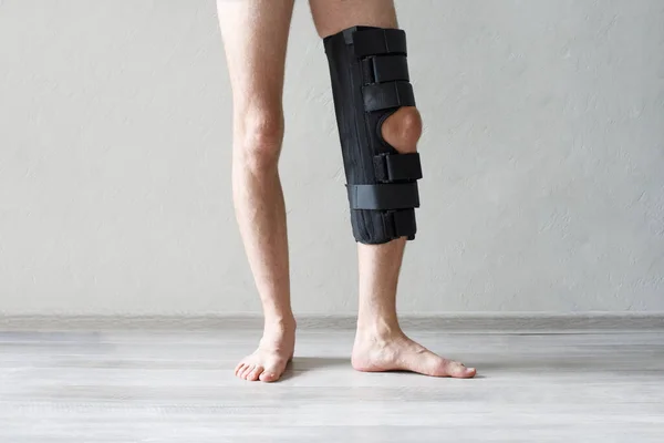 Knee support brace on a male leg. Man in an orthosis. Orthopedic anatomic braces for knee fixation, injuries and pain. Knee Joint Bandage Sleeve