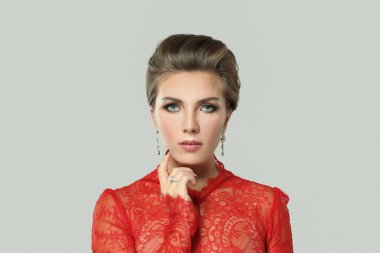 Taze, parlak tenli, sağlıklı kahverengi saçlı ve makyajlı güzel esmer kadın gri arka planda kameraya bakıyor.