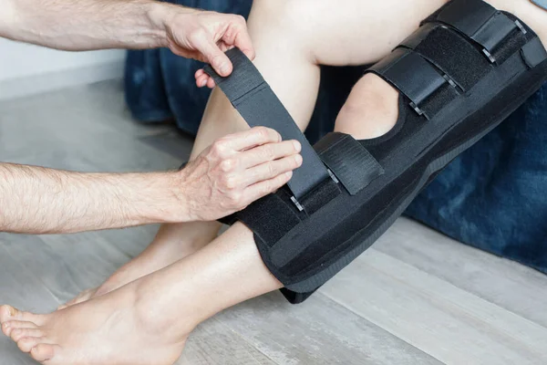 Orthopedist secures leg brace on knee, knee brace support for leg or knee injury