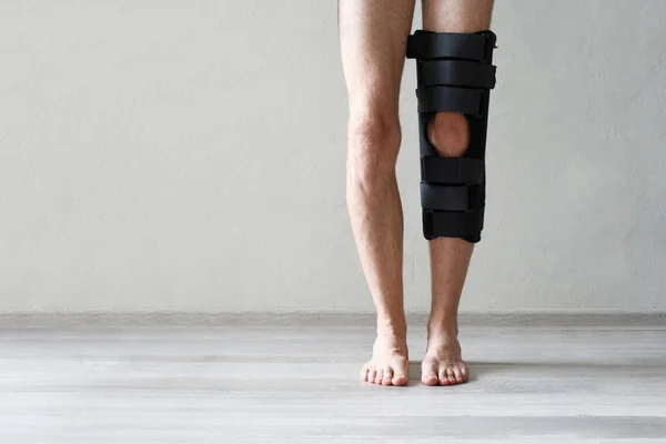 Leg brace on knee against gray wall background, knee brace support for leg or knee injury