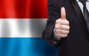 Lüksemburg konsepti. İşadamı Lüksemburg bayrağının arka planında baş parmağını gösteriyor