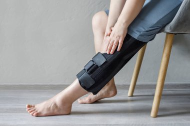 Yaralanma ve ameliyattan sonra dizlik takan kadın hasta. Sağlık ve Tıp Konsepti.