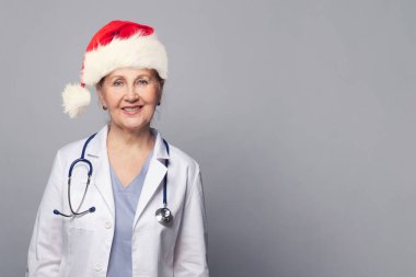 Profesyonel tıp üniforması ve kırmızı Noel Baba şapkası giyen Noel doktorunun Xmas portresi.