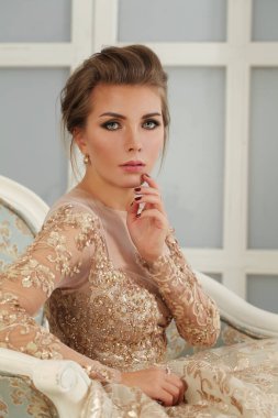 Göz kamaştırıcı zarif bir kadın. Makyajlı, altın renkli bir elbise giymiş, moda güzelliği portresi yapmış.