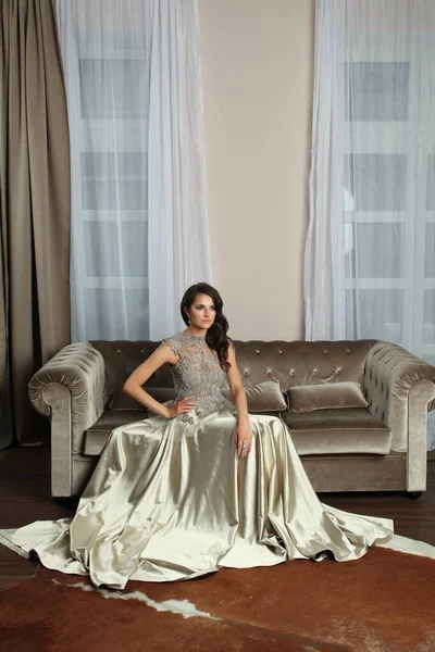 穿着晚礼服坐在内衬天鹅绒沙发上的迷人迷人的女时尚模特 — 图库照片