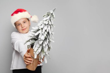 Beyaz arka planda çocukların ellerinde Karlı Noel ağacı