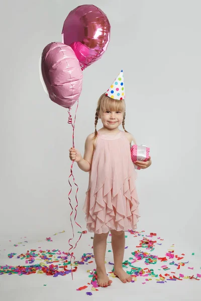 快乐快乐的笑容满面的小女孩 站在两个色彩斑斓的粉色气球旁边 背对着白色的彩色墙 生日聚会的概念 — 图库照片