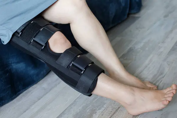 Woman in knee brace support for leg or knee injury at home, leg close up