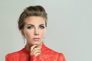 Gri arka planda elmas küpeli ve makyajlı mükemmel kadın, moda portresi.