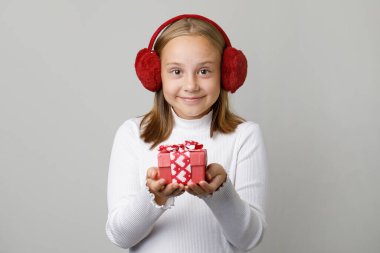 Neşeli çocuk elinde beyaz kalple kırmızı bir hediye tutuyor. Noel konsepti