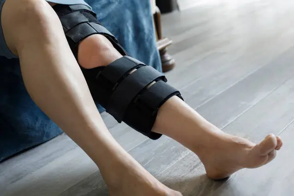 Patient wearing knee brace support after injury and surgery. Healthcare and medical concept.