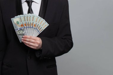 Gri arka planda Amerikan doları nakit para banknotu tutan bir işadamı.