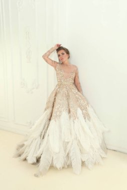 Beyaz iç çamaşırlı, beyaz ve altın bir gece elbisesi giyen, şehvetli, modaya uygun bir kadının moda portresi.