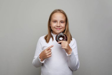 Beyaz stüdyo arka planında donut tutan sevimli küçük kız çocuğu.