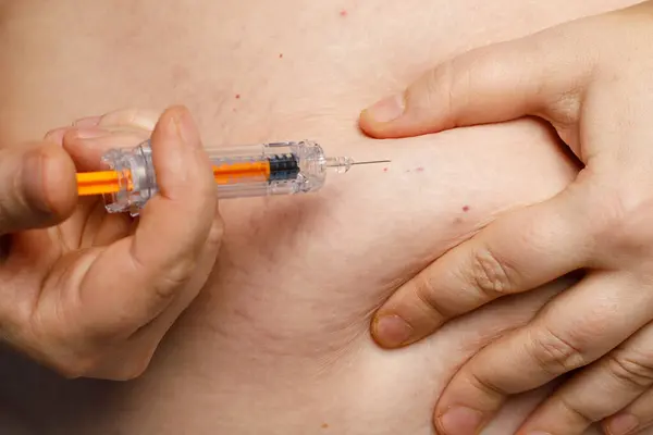 Human abdomen closeup. Person injects into self stomach with a syringe