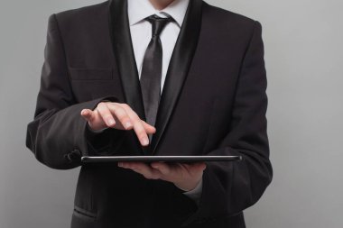 Gri arkaplanda dijital tablet kullanan iş adamı