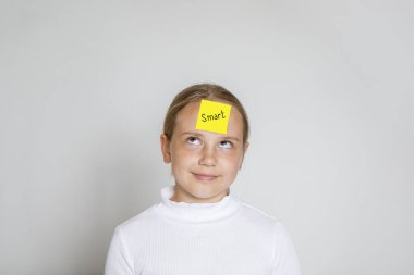 Kafasında beyaz arkaplanda akıllı yazılar olan sarı yapışkan kağıtlı sevimli çocuk.