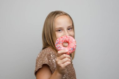 Gri arka planda pembe donutları olan tatlı bir kız çocuğu.