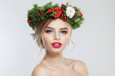 Beyaz arka planda makyajlı ve kış süslemeli güzel bir genç kadın portresi.